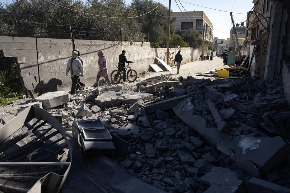 Penduduk Palestin berjalan dekat puing-puing bangunan yang musnah  akibat pengeboman Israel di khemah pelarian Palestin di Rafah, selatan Gaza pada 4 Februari.