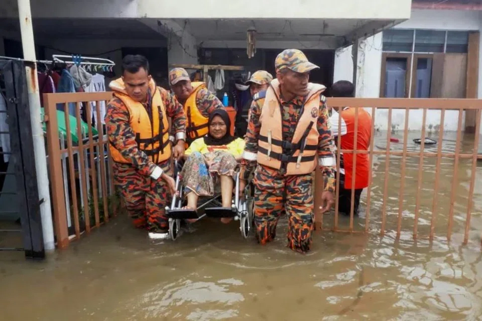 Anggota Jabatan Bomba dan Penyelamat Malaysia (JBPM) membantu memindahkan pesakit buah pinggang, Cik Nor Azizan Mohd Idin, 65 tahun (tengah) selepas rumahnya dinaiki air ekoran banjir di Taman Tanjung Bendahara, Alor Setar, Kedah.