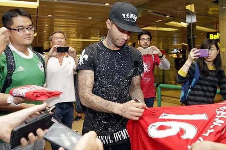 TETAP POPULAR: Bekas bintang Liverpool. Jermaine Pennant, menandatangani jersi peminatnya yang menyambut ketibaannya di Lapangan Terbang Changi pagi semalam. - Foto THE STRAITS TIMES