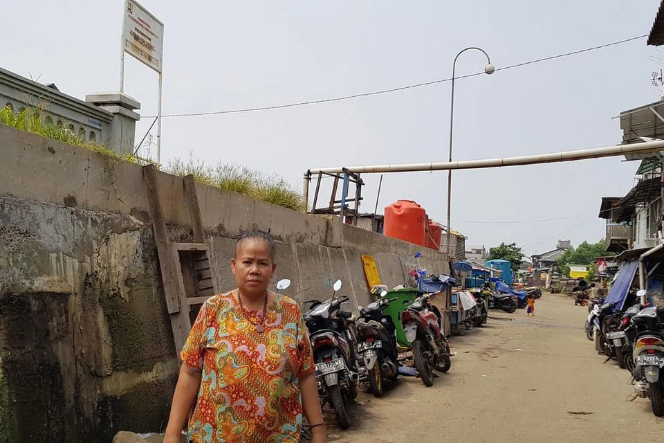 LEBIH KERAP BANJIR: Cik Daspi, di depan tembok pengukuh dekat gerainya, berkata tanah di situ telah mendap, menyebabkan kawasan pantai itu lebih sering banjir. - Foto THE STRAITS TIMES