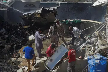 OPERASI MENYELAMAT: Pekerja penyelamat menjalankan operasi di lokasi setelah pesawat Pakistan International Airlines terhempas di kawasan perumahan di Karachi. Pesawat itu membawa lebih 100 orang. - Foto AFP