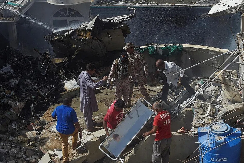 OPERASI MENYELAMAT: Pekerja penyelamat menjalankan operasi di lokasi setelah pesawat Pakistan International Airlines terhempas di kawasan perumahan di Karachi. Pesawat itu membawa lebih 100 orang. - Foto AFP
