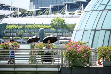 LINDUNGI DIRI: Dua wanita dilihat menggunakan payung untuk melindungi dir dari panas di kawasan Clifford Pier baru-baru ini 