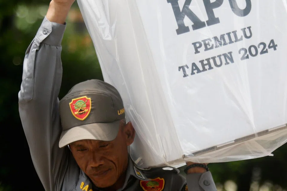 Seorang pegawai pilihan raya terpaksa mengangkut kotak undi ketika diedarkan ke pejabat daerah di Depok, Indonesia pada 12 Februari. 