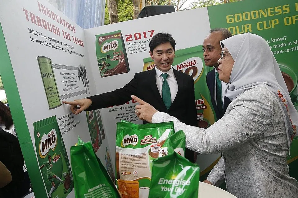 MINUMAN KEGEMARAN RAMAI: Puan Halimah diberi taklimat mengenai sejarah Milo di Singapura oleh seorang pegawai Nestle Singapura sambil diiringi Encik Rajiv ketika melancarkan serbuk terbaru, Milo Gao Kosong semalam. - Foto BH oleh TIMOTHY DAVID 
