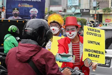 BUKAN LAWAK: Anggota kumpulan badut 'Aku Badut Indonesia (ABI)' memakai topeng muka pelindung memegang poster kempen menggalak penduduk negara itu mendapatkan vaksin Covid-19 di Depok, Jawa Barat Jumaat lalu. Indonesia mencatat lebih 3,000,000 kes Covid-19 dengan lebih 82,000 kematian sejak awal pandemik itu. - Foto EPA-EFE