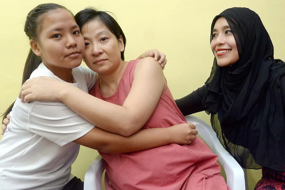 HUBUNGAN ERAT TERJALIN: Hanis Umairah Mohd Ramlan (kiri) memeluk Cik Luo Jin, ibu rakan karibnya yang telah meninggal dunia, Peony Wee Ying Ping, sambil disaksikan ibunya, Cik Hazreen Mahmood Husain. - Foto TAUFIK A. KADER