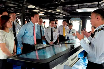 PELANCARAN KAPAL LITTORAL MISSION (LMV) KETIGA: Menteri Negara Kanan (Pertahanan), Encik Ong Ye Kung (dua dari kiri), dan isteri, Cik Diana Ong (kiri), dan Panglima Angkatan Laut Singapura, Laksamana Lai Chung Han (empat dari kanan), mendengar taklimat Ketua Pejabat Projek LMV Angkatan Laut Singapura, Leftenan-Kolonel Chew Chun-Chau (kanan), semasa lawatan ke Pusat Kawalan Bersepadu kapal. - Foto MINDEF