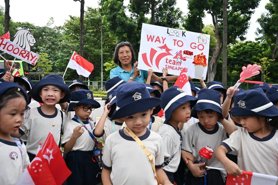 
Ibu Maximilian Maeder, Cik Teng Hwee Keng (di tengah, berbaju biru) berinteraksi bersama kanak-kanak daripada Akademi Pra-Sekolah Enfant sambil menunggu di sepanjang Victoria Street (dinding mural berhampiran Muzium Kamera) untuk perarakan bas terbuka bagi meraikan atlet Olimpik Pasukan Singapura, termasuk anak beliau, seorang pemenang pingat gangsa.
