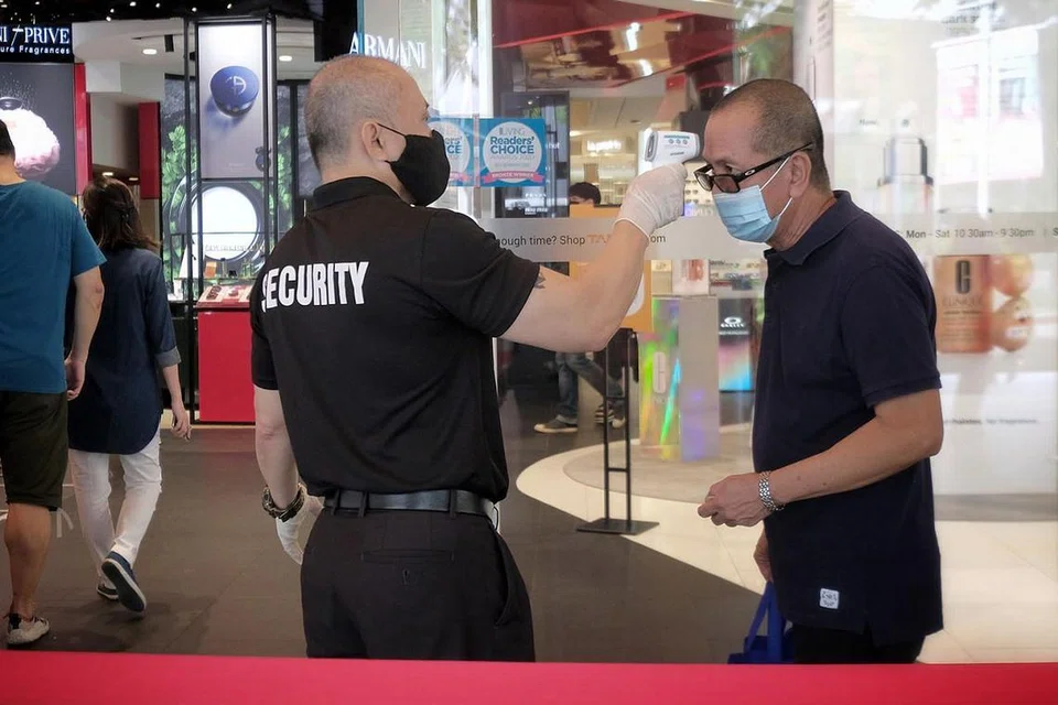 LANGKAH BERJAGA-JAGA: Suhu badan seorang pengunjung ke pusat beli-belah Tang's di Orchard Road pada Jumaat lalu diambil oleh pegawai keselamatan sebelum dibenarkan masuk. - Foto BM oleh GAVIN FOO