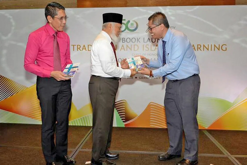 LANCAR BUKU: Penerima Anugerah Cendekiawan Syed Isa Semait, Dr Norshahril Saat (kanan), menyampaikan bukunya bertajuk 'Tradition and Islamic Learning: Singapore Students in the Al-Azhar University (Tradisi dan Pembelajaran Islam: Pelajar Singapura di Universiti Al-Azhar)' kepada mantan Mufti Syed Isa Semait (tengah). Turut hadir di pelancaran buku itu Jumaat lalu ialah Menteri Negara Kanan (Pertahanan merangkap Ehwal Luar), Dr Mohamad Maliki Osman (kiri). - Foto MUIS