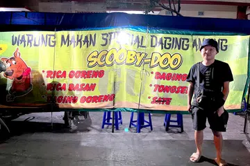 Seorang pelancong bergambar di depan gerai yang menjual daging anjing di Solo, Jawa Tengah. 