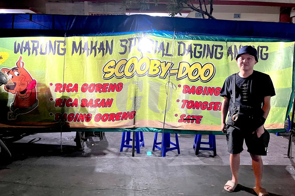 Seorang pelancong bergambar di depan gerai yang menjual daging anjing di Solo, Jawa Tengah. 