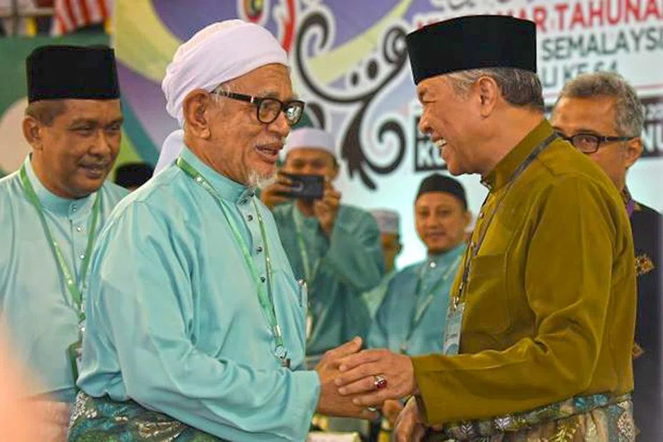 TOLONG-MENOLONG ATAU KERJASAMA POLITIK?: Presiden PAS, Datuk Seri Abdul Hadi Awang (kiri), dan presiden Umno, Datuk Seri Dr Ahmad Zahid Hamidi, bersalaman di muktamar tahunan parti Islam itu hujung minggu lalu. Itu kali pertama seorang pemimpin Umno menghadiri muktamar PAS. - Foto THE STAR