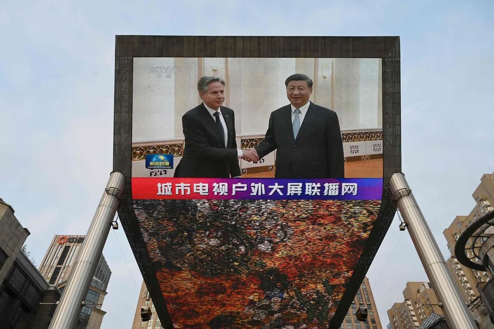 PERTEMUAN SIMBOLIK: Stesen China Central Television menyiarkan berita mengenai pertemuan Setiausaha Negara Amerika Syarikat, Encik Antony Blinken (kiri), dengan Presiden China, Encik Xi Jinping menerusi skrin gergasi di luar sebuah pusat membeli-belah di Beijing. 
