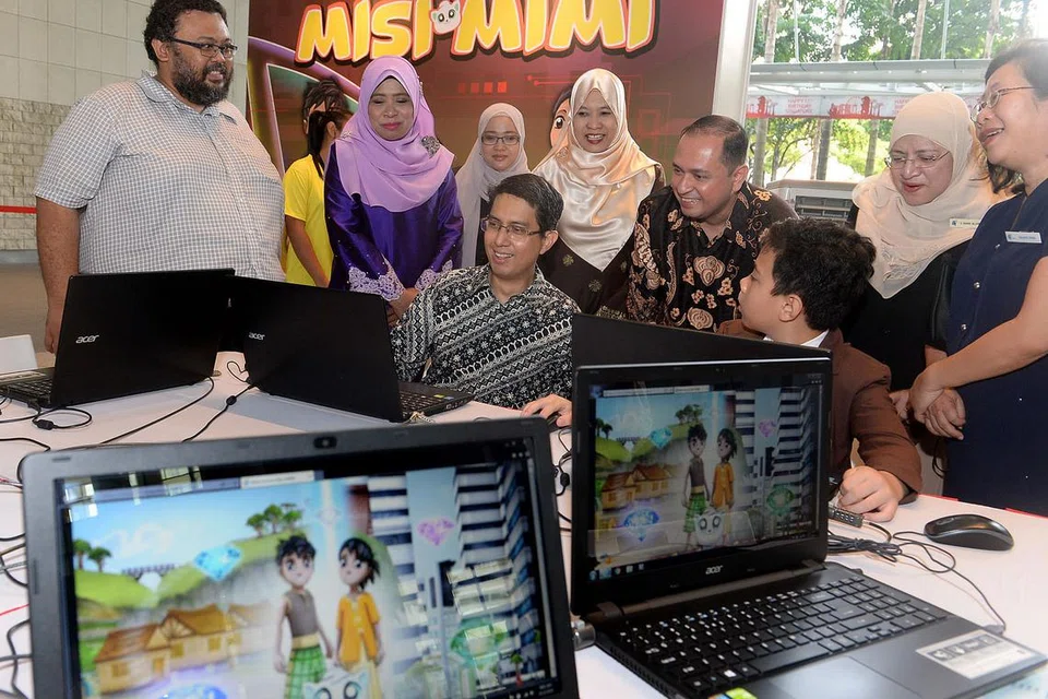 BERMAIN SAMBIL BELAJAR: Profesor Madya Muhammad Faishal Ibrahim (duduk, kiri) cuba menjawab soalan bahasa yang ditanya melalui portal permainan bahasa Melayu, Misi Mimi, yang dilancarkan dalam 'Fiesta Bahasa 2016' semalam. Fiesta itu berlangsung di The Plaza, bangunan Perpustakaan Negara. - Foto TAUFIK A. KADER