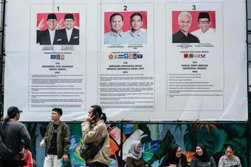 BAKAL MEMILIH: Orang ramai duduk di bawah poster tiga pasangan calon presiden dan naib presiden menjelang Pilihan Raya Umum Indonesia yang dijadualkan pada 14 Februari 2024 dekat pejabat Suruhanjaya Pilihan Raya Umum Indonesia (KPU) di Jakarta pada 2 Januari. 