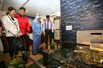 PUSAT BARAH BARU: Presiden Halimah (dua dari kanan) mendengar taklimat Ketua Pegawai Eksekutif Persatuan Ain, Haji Md Yusof Ismail (kanan), mengenai tarikan baru pusat kedua persatuan itu. 