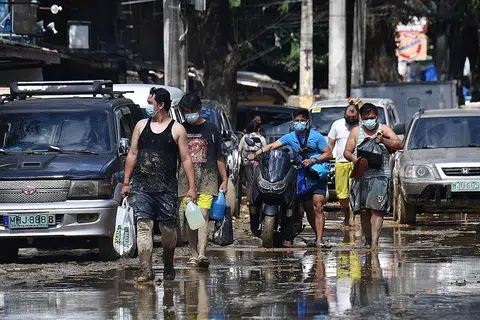 MANGSA BENCANA ALAM: Penduduk Marikina City berdekatan Manila membawa bekalan makanan pulang ke rumah pada 13 November lalu, sehari selepas taufan Vamco melanda kawasan itu. - AFP
