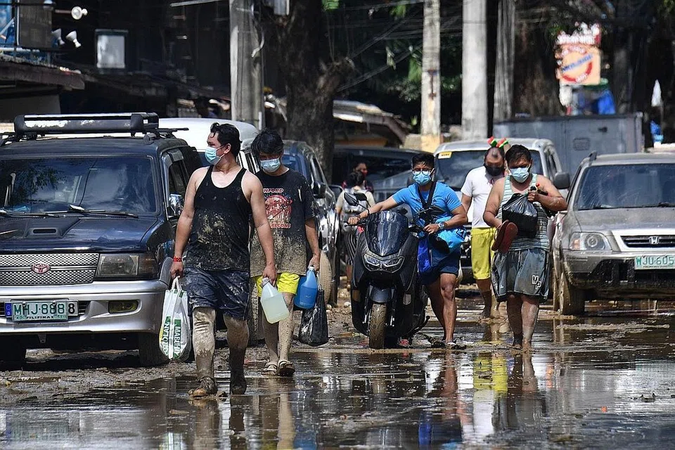 MANGSA BENCANA ALAM: Penduduk Marikina City berdekatan Manila membawa bekalan makanan pulang ke rumah pada 13 November lalu, sehari selepas taufan Vamco melanda kawasan itu. - AFP