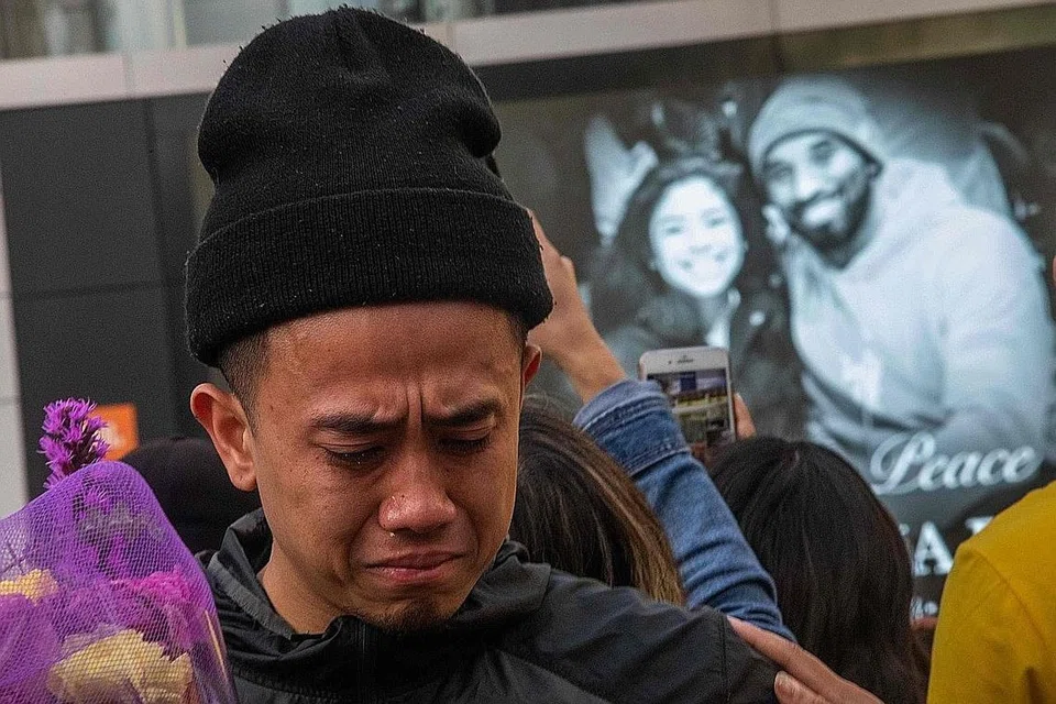 PEMERGIAN DITANGISI: Kesedihan terpapar pada wajah peminat apabila mereka berkumpul di peringatan sementara di kompleks hiburan LA Live, bertentangan Pusat Staples - rumah pasukan Los Angeles Lakers - di Los Angeles, California, untuk memberi penghormatan kepada Kobe Bryant, yang gambar beliau serta anak perempuannya Gianna turut dipaparkan (gambar atas). - Foto EPA-EFE, AFP