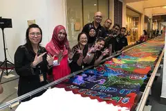 CIPTA REKOD: Encik Kamal (enam dari kiri) bersama mereka yang terlibat dalam acara Batik Masyarakat yang berjaya mencipta rekod batik terpanjang di Singapura pada tahun lalu di Nafa. - Foto ihsan KAMAL DOLLAH