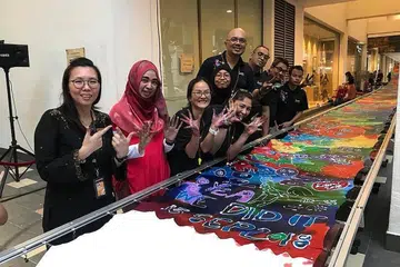 CIPTA REKOD: Encik Kamal (enam dari kiri) bersama mereka yang terlibat dalam acara Batik Masyarakat yang berjaya mencipta rekod batik terpanjang di Singapura pada tahun lalu di Nafa. - Foto ihsan KAMAL DOLLAH