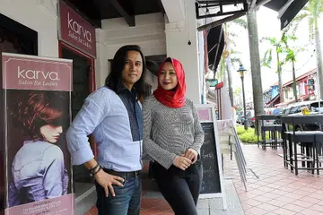 TERUS BERKEMBANG: Jai Wahab dan Rozza Ramli di luar salun cawangan Bussorah Street mereka. Pasangan selebriti ini mahu mengembangkan salun mereka ke utara Singapura dan luar negara. - Foto SHAHRIYA YAHAYA