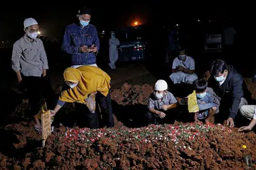 KEHILANGAN BAPA: Dua kanak-kanak menghadiri pengebumian bapa mereka, yang meninggal dunia akibat Covid-19, bersama ibu mereka di tanah perkuburan yang disediakan pemerintah di Bekasi, di luar Jakarta, pada 27 Julai. - Foto REUTERS