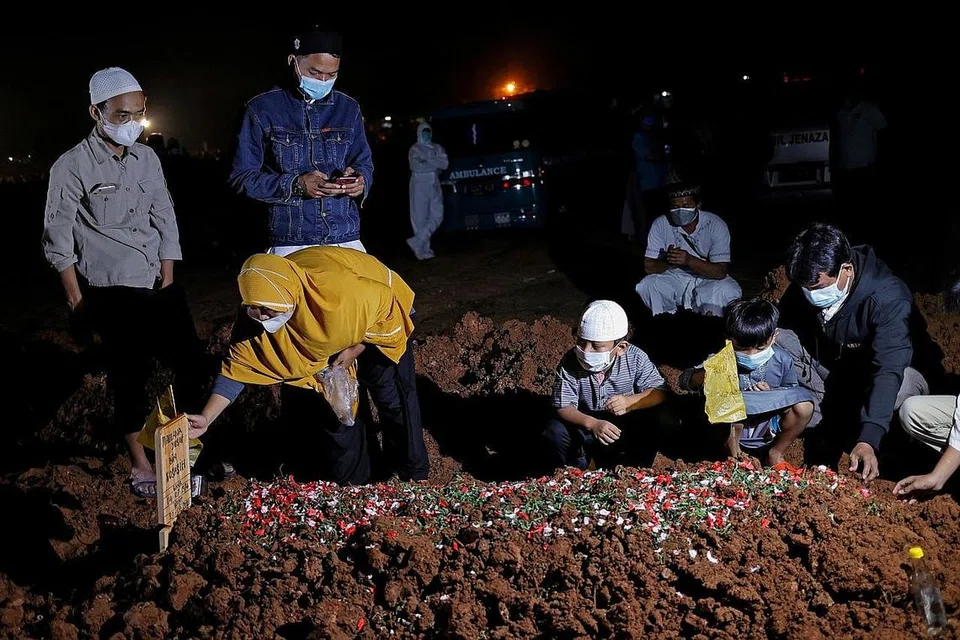 KEHILANGAN BAPA: Dua kanak-kanak menghadiri pengebumian bapa mereka, yang meninggal dunia akibat Covid-19, bersama ibu mereka di tanah perkuburan yang disediakan pemerintah di Bekasi, di luar Jakarta, pada 27 Julai. - Foto REUTERS
