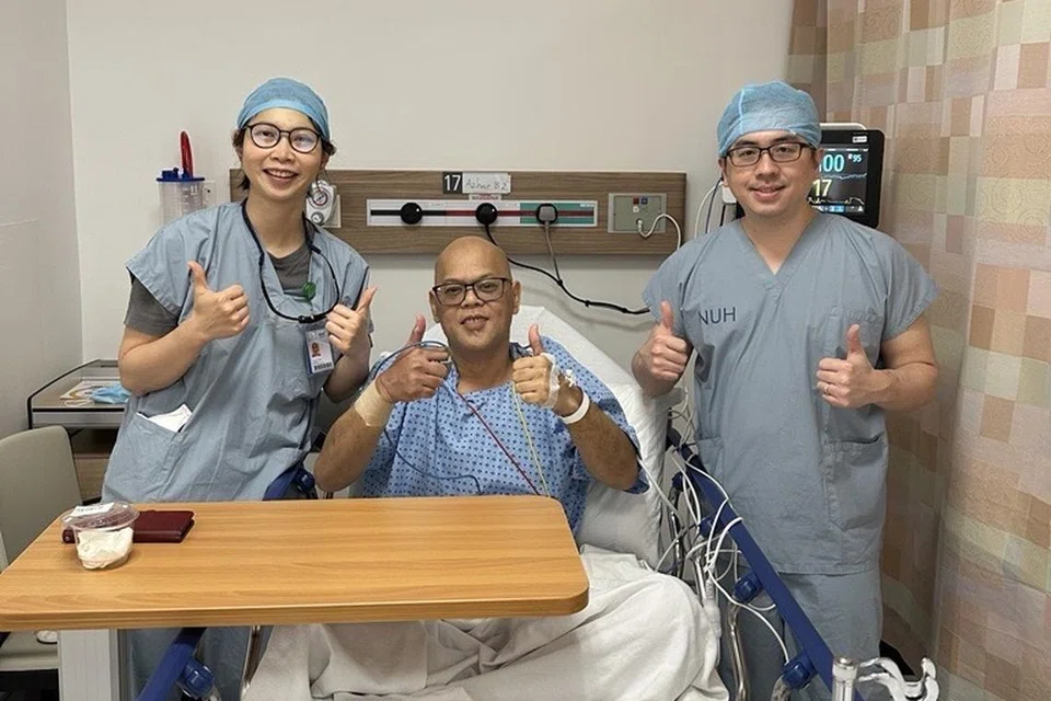 Encik Azhar Zainal (tengah) selepas menjalani pembedahan Intervensi Koronari Perkutan (PCI) di Hospital Universiti Nasional (NUH) pada November 2024. Beliau ditemani Penolong Jururawat Klinikal, Cik Yap El Fuon (kiri), dan Pengarah Klinikal Pusat Kardiologi Intervensi dan Angiografi di NUHCS, Penolong Profesor Gavin Ng. 