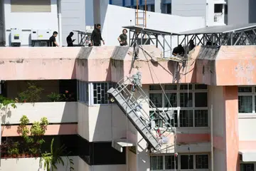 HAMPIR JATUH: Sebuah gondola condong dan tergantung selepas sebahagian daripada tembok di bumbung blok HDB di Boon Lay runtuh.