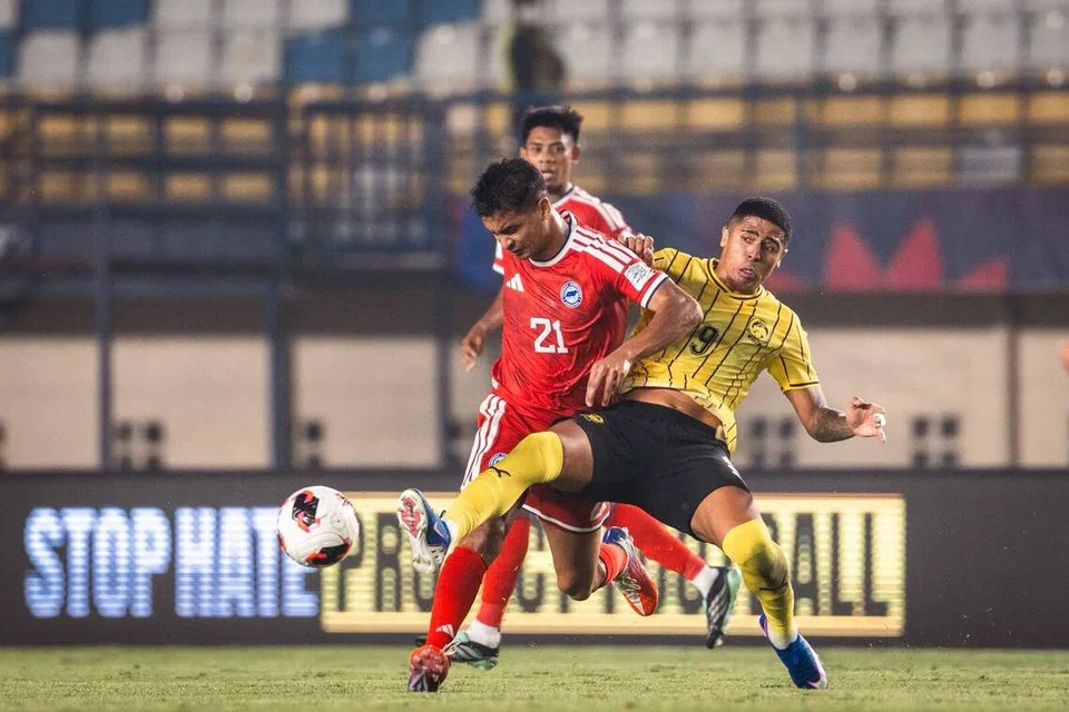Pasukan Singa (jersi merah) cuba mengatasi asakan pemain Harimau Malaya ketika perlawanan Kumpulan A Piala Asean FIFA. Singa akhirnya ditundukkan 6-0. Keputusan itu bermakna Singa tersingkir daripada kejohanan tersebut