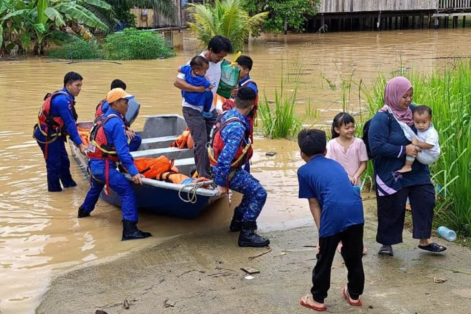 Anggota Angkatan Pertahanan Awam Malaysia (APM) membantu penduduk di Sook, Sabah, berpindah ke tempat selamat selepas kediaman mereka ditenggelami banjir.