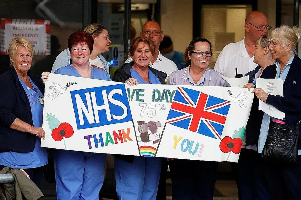 DIBERI PENGHARGAAN: Pekerja penjagaan kesihatan Britian menerima kain rentang yang menghargai usaha mereka dalam memerangi wabak penularan Covid-19 di negara itu. - Foto REUTERS