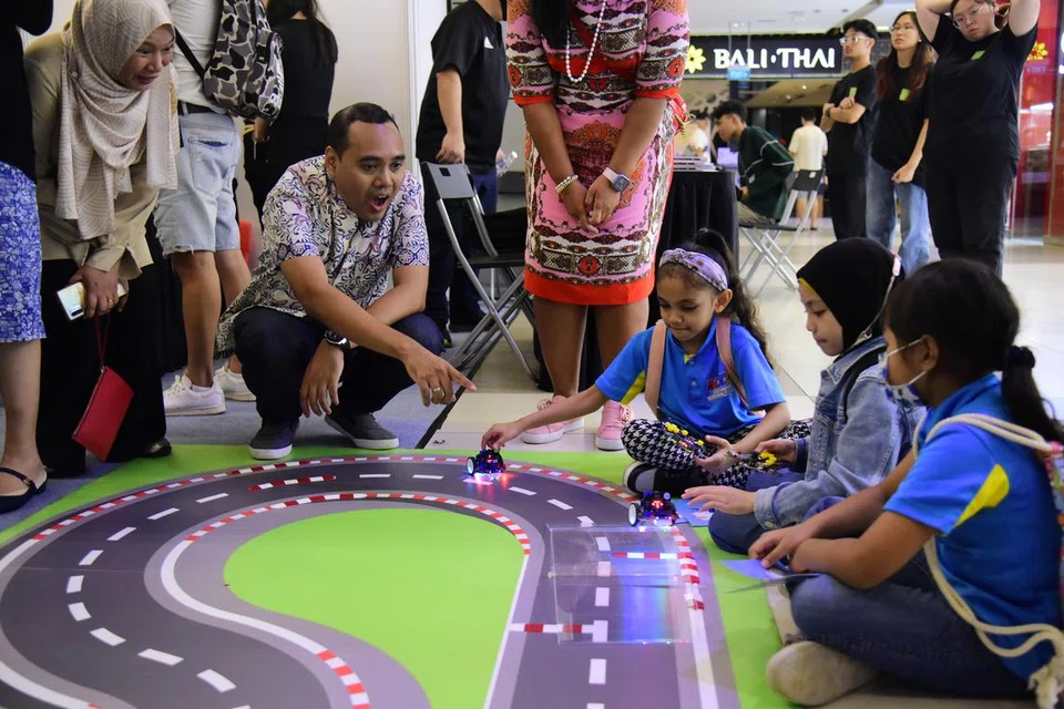 LUMBA KERETA: Anggota Parlimen GRC Chua Chu Kang, Encik Zhulkarnain Abdul Rahim (dua dari kiri), melihat kanak-kanak melumba kereta elektrik mereka. 