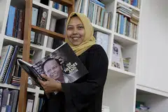 JASA AYAH: Ayahnya, Allahyarham Harun Abdul Ghani, yang gambarnya di buku yang dipegang Cik Haslinda (kiri), merupakan antara orang yang mendorongnya untuk teruskan usaha membantu anak-anak pesalah dadah.
