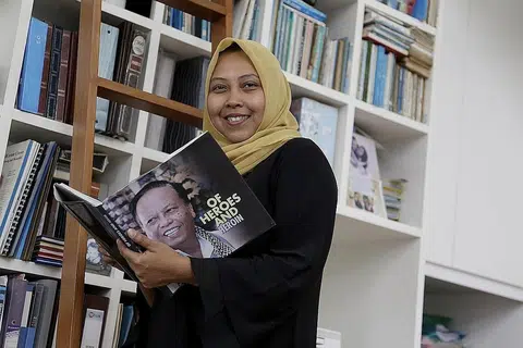 JASA AYAH: Ayahnya, Allahyarham Harun Abdul Ghani, yang gambarnya di buku yang dipegang Cik Haslinda (kiri), merupakan antara orang yang mendorongnya untuk teruskan usaha membantu anak-anak pesalah dadah.