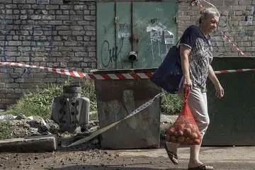 KESAN SERANGAN: Seorang wanita setempat jalan melintasi serpihan roket selepas serangan di bandar Mykolaiv, Ukraine. - Foto EPA-EFE