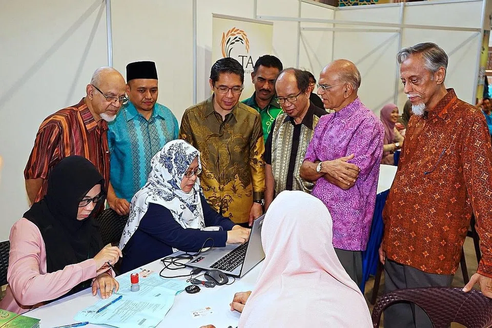 BANTU MASYARAKAT: Dr Maliki (berdiri tiga dari kiri) bersama pemimpin masyarakat Melayu/Islam dalam satu acara Tabung Amal Aidilfitri (TAA) tahun lalu. - Foto fail TAA
