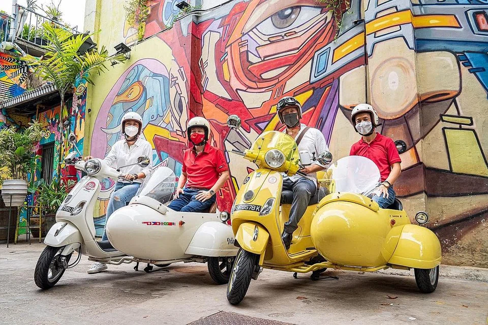 BANTU INDUSTRI: Ketua Negeri DBS Singapore, Encik Shee Tse Koon (kiri, berbaju merah); dan Ketua Eksekutif STB, Encik Keith Tan (kanan, berbaju merah), menyertai sebuah lawatan bersama Lawatan Vespa Kereta Sisi (Sidecar) Singapura. Kerjasama DBS-STB bertujuan memberi rangsangan kepada perniagaan pelancongan melalui kempen dalam negeri dan antarabangsa, serta memangkin pembangunan industri pelancongan. - Foto DBS BANK