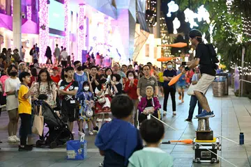 Seorang seniman jalanan melakukan persembahan yang menarik ramai penonton di Orchard Road.