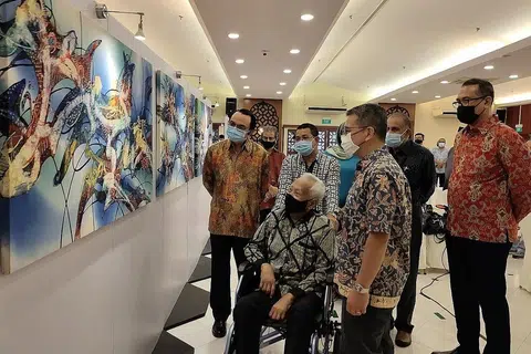 SUMBANGAN DIHARGAI: Encik Sarkasi Said (berkerusi roda) melihat lukisan batik beliau yang dipamer di bangunan Jamiyah dengan diiringi Encik Edwin Tong dan Dr Mohd Hasbi Abu Bakar (kiri dan kanan beliau). - Foto BH oleh NUR DHUHA ESOOF