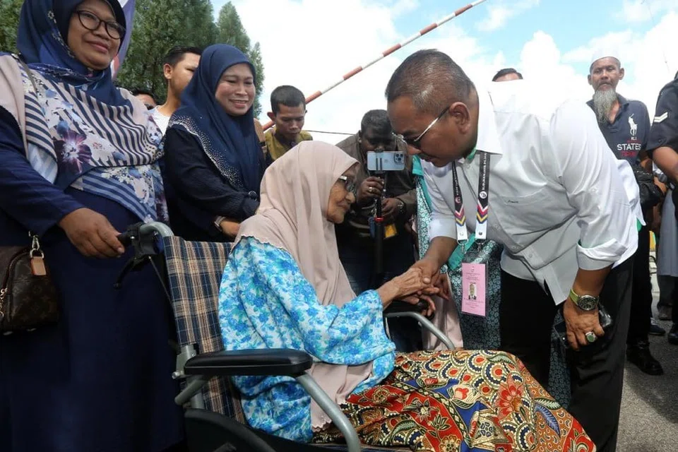POPULAR DALAM KALANGAN PENGUNDI: Datuk Seri Muhammad Sanusi (kanan), datang ke pusat mengundi bersama isteri, Tok Puan Jusmalailani Jusoh (terlindung di belakang Datuk Sanusi), dan disambut meriah oleh pengundi di Dewan Undangan Negeri Jeneri.