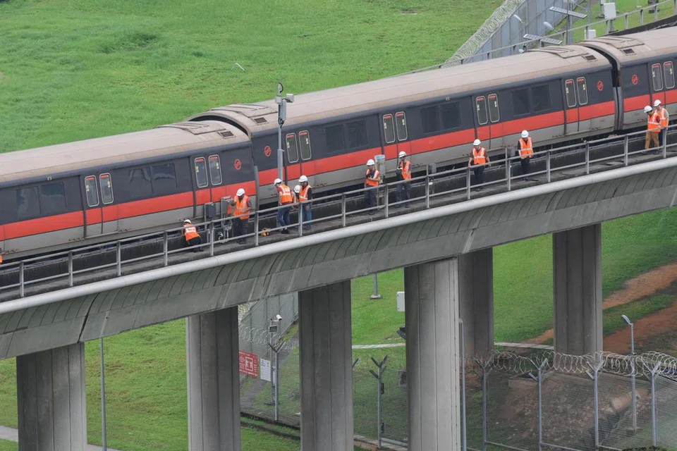 Kakitangan SMRT memeriksa gerabak kereta api terjejas di luar Depot Ulu Pandan kira-kira jam 1.45 tengah hari pada 25 September. 