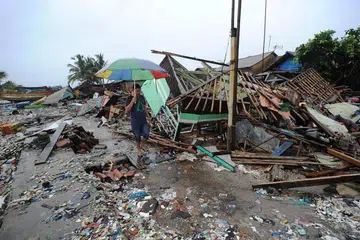 MUSNAH: Seorang lelaki berjalan di hadapan sebuah rumah yang musnah di kampung Teluk di Banten.