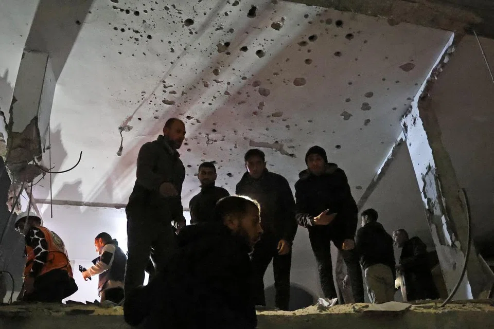 Penduduk Gaza memeriksa lokasi serangan udara Israel ke atas sebuah rumah di Khan Younis, selatan Jaluran Gaza, pada 7 Januari, di tengah-tengah perang yang sedang berlangsung di wilayah Palestin antara Israel dengan Hamas. 