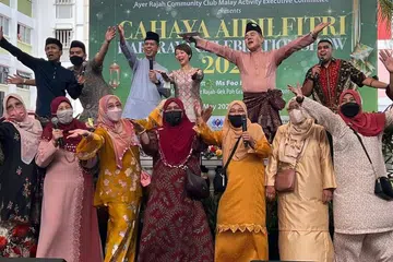 DEKATI MASYARAKAT: Encik Shahrin (barisan belakang tiga dari kiri) bersama Anggota Parlimen GRC West Coast Cik Foo Mee Har (barisan belakang, empat dari kiri) membuat persembahan bersama penduduk sempena majlis sambutan Hari Raya Aidilfitri anjuran MAEC Kelab Masyarakat Ayer Rajah . - Foto MAEC KELAB MASYARAKAT AYER RAJAH