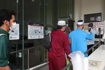 JEJAK KONTAK: Jemaah di Masjid Maarof semalam mendaftar masuk untuk solat Jumaat menggunakan sama ada token atau aplikasi di telefon bimbit jejak kontak TraceTogether. Mereka tidak boleh menggunakan aplikasi SafeEntry atau kad pengenalan. - Foto BH oleh TIMOTHY DAVID