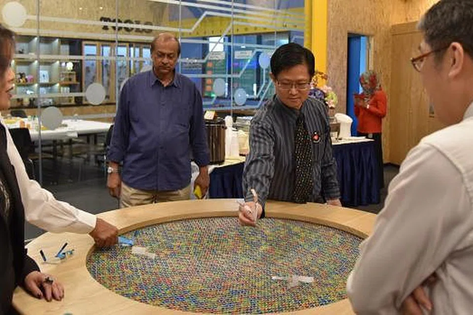 MENGGUNAKAN TENAGA ANGIN: Ketua Eksekutif Pusat Sains Singapura (SSC), Profesor Madya Lim Tit Meng (dua dari kanan), cuba melayangkan objek di salah satu tarikan bernama Wind Table di Tinkering Studio di SSC. - Foto PUSAT SAINS SINGAPURA